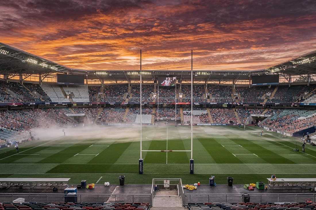 Empty rugby stadium at twilight with dramatic sky evoking decades of World Cup history and tradition